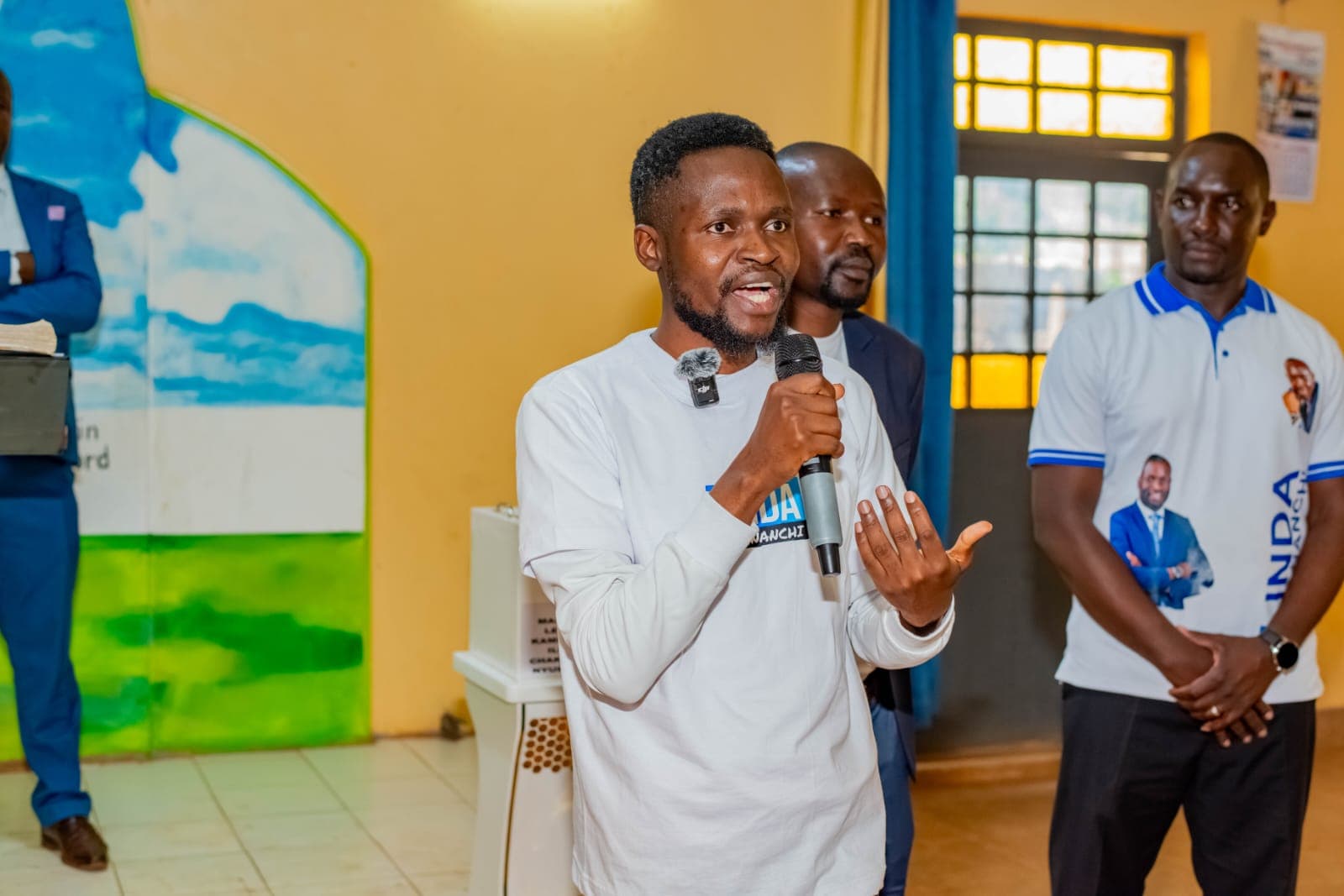 Oburenyi Harrison addressing a community meeting with a microphone